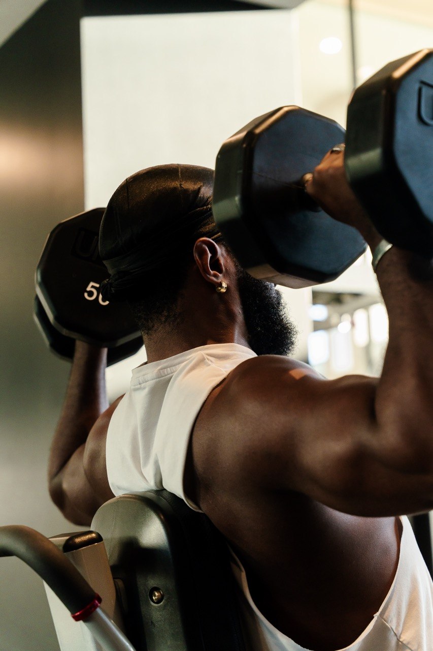 Rear view of Sampson performing a shoulder press for Day 7